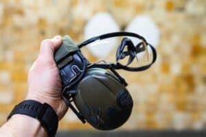 Electronic shooting earmuffs and clear protective glasses held at an indoor range.